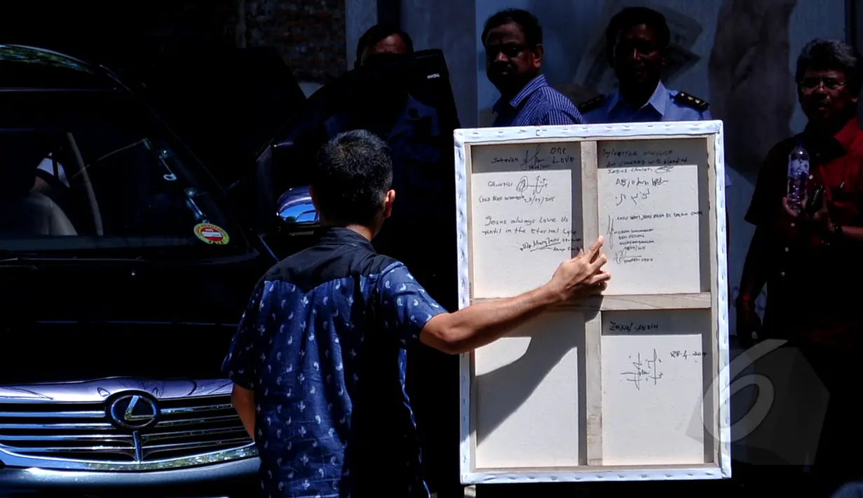 Narapidana yang akan dieksekusi mati menuliskan pesan di balik lukisan karya  Myuran Sukumaran, Nusakambangan, Jawa Tengah, Selasa (28/4/2015) . Lukisan itu merupakan lukisan terakhir Myuran (Liputan6.com/Yoppy Renato)