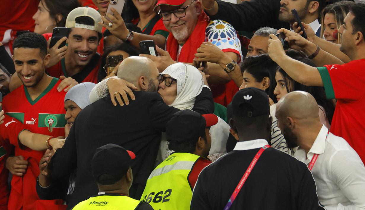 Pelatih Maroko,Walid Regragui (kiri) merayakan kemenangan bersama ibunya setelah timnya berhasil mengalahkan Portugal pada laga perempat final Piala Dunia 2022 yang berlangsung di Al Thumama Stadium, Qatar, 10 Desember 2022. (AFP/Odd Andersen)