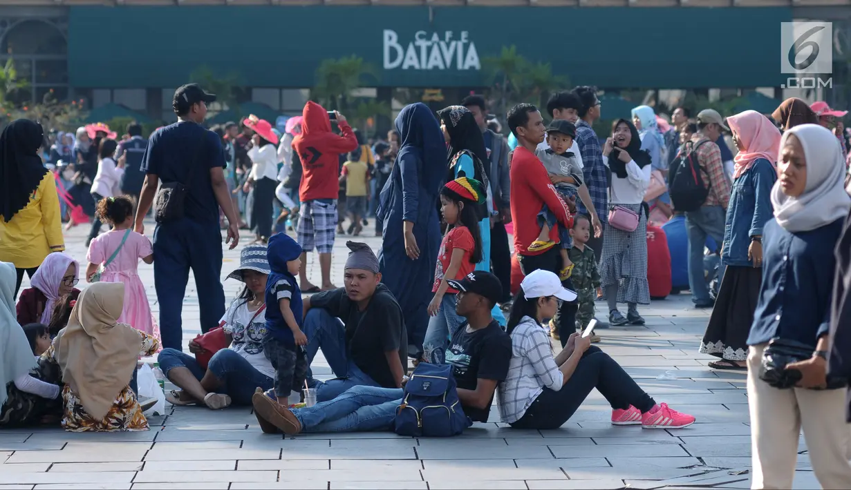 Warga duduk beristirahat di pelataran Museum Fatahillah, Jakarta, Selasa (19/6). Kemudahan transportasi dan biaya yang murah menjadikan kawasan ini sebagai lokasi favorit warga untuk menghabiskan waktu libur. (Liputan6.com/Helmi Fithriansyah)