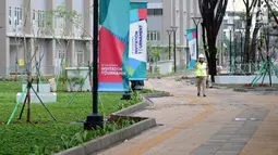 Pekerja melintas di sekitar taman wisma atlet Asian Games 2018, Kemayoran, Jakarta, Minggu (4/2). Pembangunan rusun yang akan digunakan sebagai Wisma Atlet pada Asian Games 2018 telah dinyatakan selesai 100 persen. (Liputan6.com/Helmi Fithriansyah)