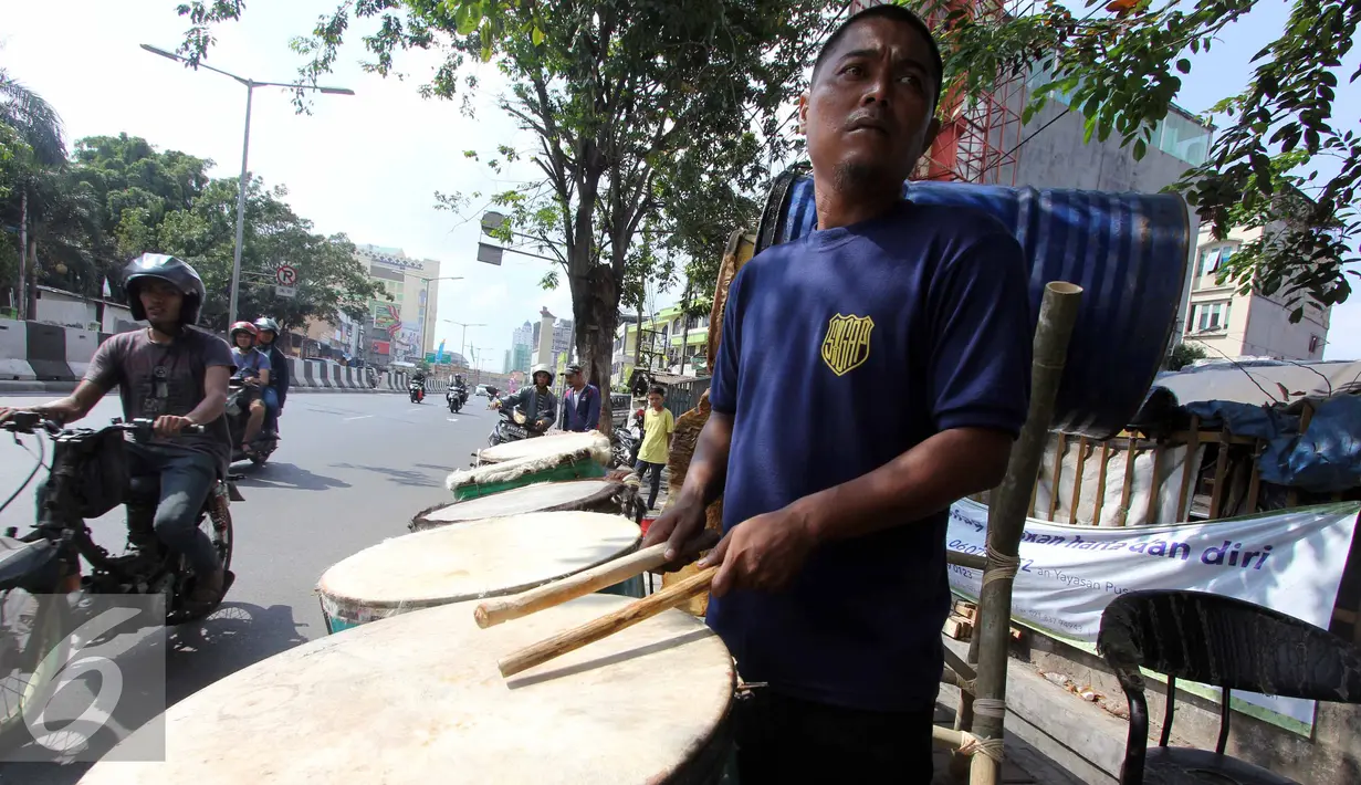 Seorang pedagang bedug tampak mencoba bedug dagangannya, Tanah Abang, Jakarta, Kamis,(16/7/2015). Harga bedug berkisar Rp.200-700 Ribu tergantung ukuran. (Liputan6.com/Helmi Afandi)
