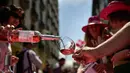 Seorang wanita menuangkan anggur mawar Spanyol untuk mempromosikan minuman tersebut di Pamplona, Spanyol, Sabtu (19/5). Acara ini dilakukan pada musim semi yang cerah. (AP Photo/Alvaro Barrientos)