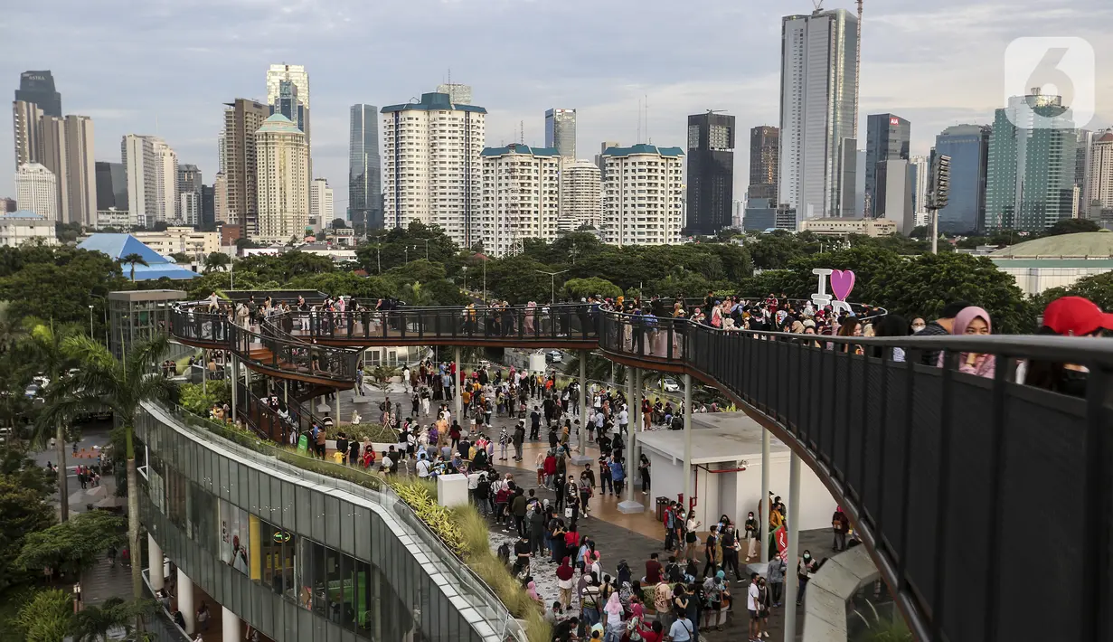 Warga mengisi libur Tahun Baru dengan menikmati pemandangan Kota Jakarta dari Skywalk Senayan Park, Sabtu (1/1/2022). Skywalk Senayan Park kini menjadi salah satu tempat wisata pilihan warga Jakarta lantaran pemandangannya yang instagramable. (Liputan6.com/Johan Tallo)