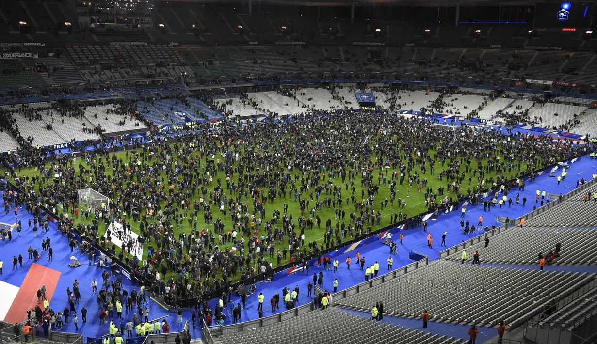 Ribuan Penonton berhamburan di lapangan stadion Stade de France saat menyaksikan pertandingan persahabatan antara Prancis melawan Jerman di Saint-Denis, Paris, (13/11). Serangan bom terjadi di dekat stadion Stade de France Prancis. (AFP PHOTO/FRANCK FIFE)