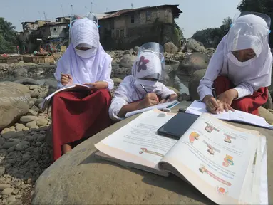 Siswa kelas 3 SDN II Roda Kota Bogor dan pendamping belajar kelompok secara daring di pinggir sungai Ciliwung, Kampung Kebon Jukut RT 01/10, Babakan Pasar, Kamis (6/8/2020). Belajar di pinggir sungai Ciliwung itu guna mendapatkan jaringan internet yang baik di masa pandemi. (merdeka.com/Arie Basuki)