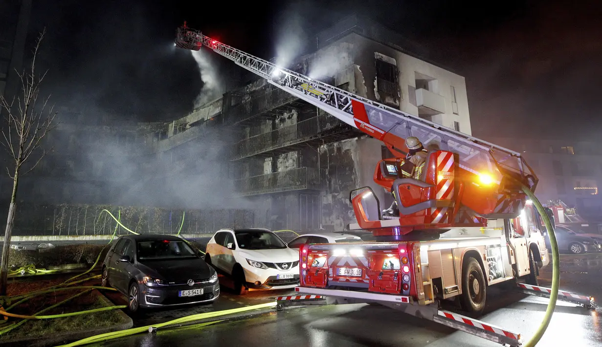 Petugas pemadam kebakaran memadamkan api di kompleks perumahan di Essen Jerman, Senin (21/2/2022). Sekitar 150 petugas dikerahkan untuk memadamkan api. (Roland Weihrauch/dpa via AP)