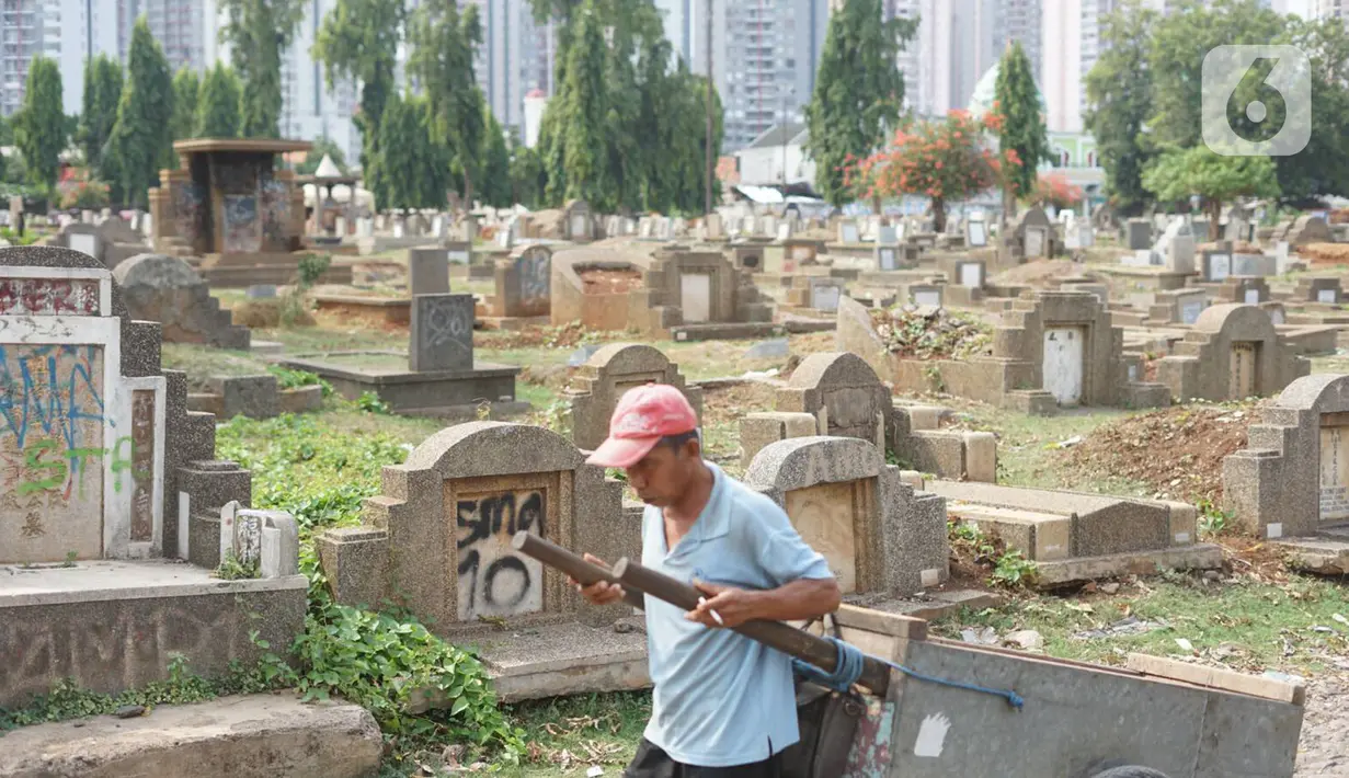 Seorang pria dengan membawa gerobak melintas di sekitar Taman Pemakaman Umum (TPU) Menteng Pulo, Jakarta, Selasa (3/12/2019). Pemprov DKI Jakarta berencana merevitalisasi 17 TPU serta akan melakukan perluasan lahan makam hingga 794,83 hektar. (Liputan6.com/Immanuel Antonius)
