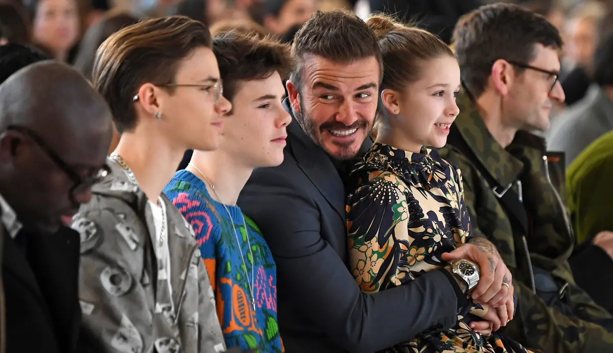 David Beckham bersama anak-anaknya Romeo Beckham, Cruz Beckham dan Harper saat menghadiri peragaan busana Musim Gugur/Musim Dingin 2020 Victoria Beckham dalam acara London Fashion Week di London, (16/2/2020). Beckham tampil dengan setelan jas hitam. (AFP/Daniel Leal-Olivas)