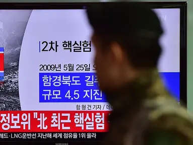 Tentara Korea Selatan berjalan melewati sebuah layar TV yang menunjukkan laporan berita di sebuah stasiun kereta api di Seoul, Rabu (6/1/2016). Gempa berkekuatan 5,1 SR terdeteksi di dekat tempat uji coba nuklir Korea Utara. (AFP PHOTO/Jung Yeon-Je)