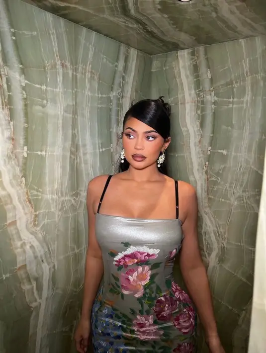 Senada dengan sang kakak, Kylie Jenner mengenakan spaghetti strap dress dengan motif bunga serupa warna sage. Tampilannya diperlengkap dengan high ponytail with side bangs. (Instagram/kyliejenner).