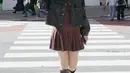 Aaliyah mengenakan mini dress coklat dengan bagian rok model pleated. Dipadukan jaket leather senada dengan knee bootsnya. [@aaliyah.massaid]