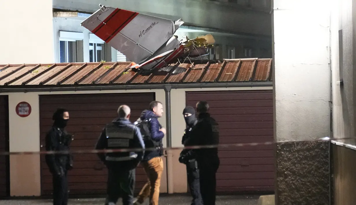 Petugas polisi berdiri di dekat ekor pesawat kecil yang melakukan pendaratan darurat di sebuah kediaman, di Villejuif, luar Paris, Senin (4/12/2023). (AP Photo/Michel Euler)