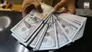 Pekerja menunjukan Dolar AS di jasa penukaran uang asing di Jakarta, Rabu (19/6/2019). Nilai tukar rupiah terhadap Dolar AS sore ini Rabu (19/6) ditutup menguat sebesar Rp 14.269 per dolar AS atau menguat 56,0 poin (0,39 persen) dari penutupan sebelumnya. (Liputan6.com/Angga Yuniar)