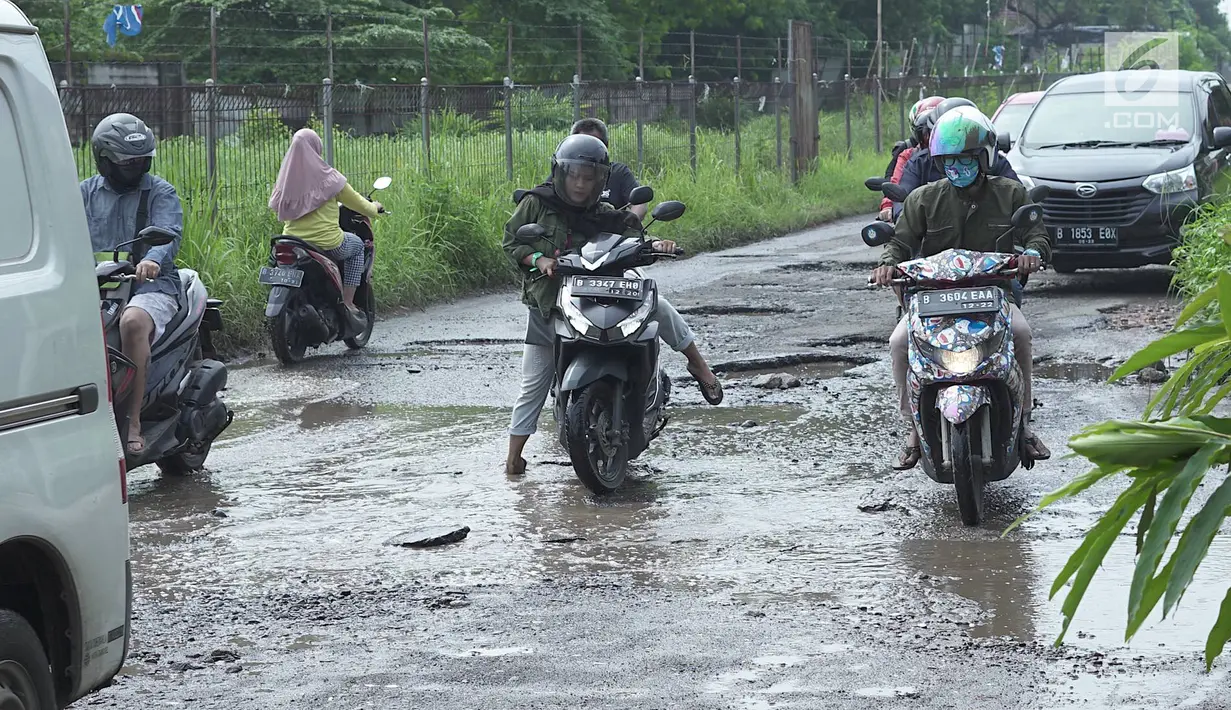 Pengendara motor berusaha menghindari jalan rusak yang menjadi kubangan air di Jalan Raya Gas Alam, Depok, Jawa Barat, Selasa (7/5). Kondisi jalan yang tidak kunjung diperbaiki tersebut menjadi kubangan air setiap hujan serta berbahaya bagi keselamatan pengguna jalan (Liputan6.com/Immanuel Antonius)