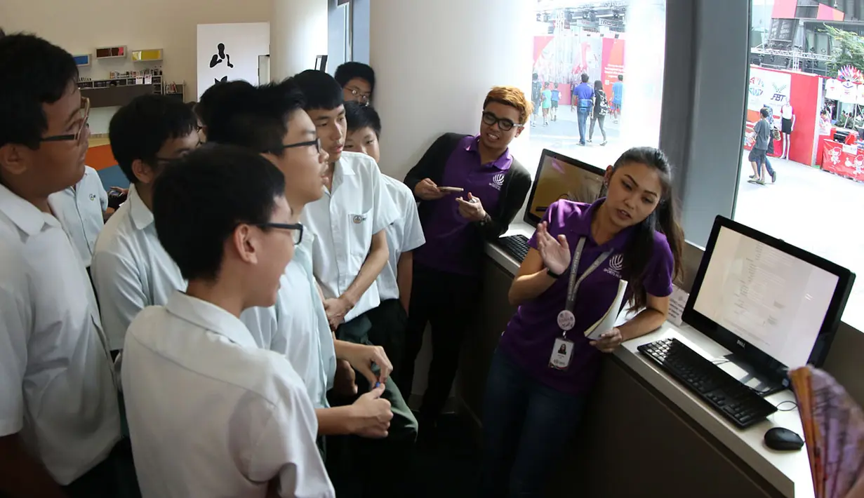 Petugas memberikan penjelasan kepada pengunjung tentang koleksi ribuan buku di Perpustakaan Olah Raga Singapura yang terletak di Pusat Olah Raga Singapura (Singapore Sports Hub). (Bola.com/Arief Bagus)