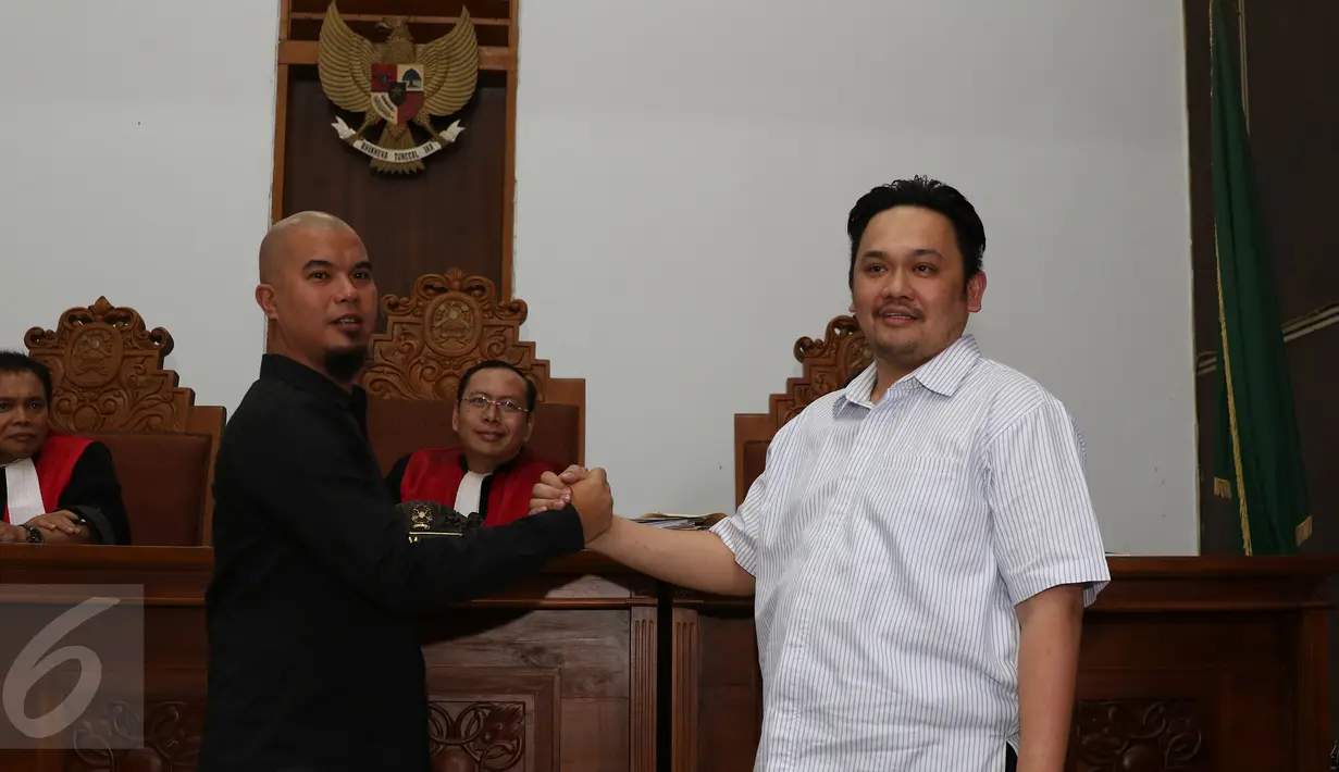 Musisi Ahmad Dhani dan Farhat Abbas melakukan salam komando seusai menjalani sidang lanjutan kasus pencemaran nama baik yang dilayangkan Ahmad Dhani di Pengadilan Negeri Jakarta Selatan, Kamis (19/11). (Liputan6.com/Herman Zakharia)