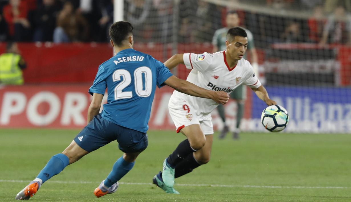 Pemain Real Madrid, Asensio (kiri) berusaha menahan laju pemain Sevilla, Ben Yedder pada laga La Liga Santander di Sanchez Pizjuan stadium, Seville, (9/5/2018). Madrid kalah 2-3 dari Sevilla.  (AP/Miguel Morenatti)