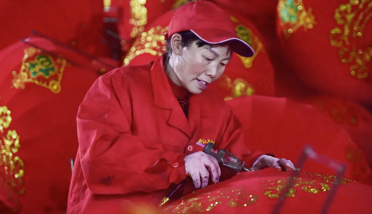 Seorang pekerja membuat lentera merah menjelang perayaan Tahun Baru Imlek 2020 di sebuah pabrik di Wuyi, China, Kamis (26/12/2019). Beberapa keunikan pada tradisi perayaan Imlek yang masih dijalani warga Tionghoa adalah menggantung lentera merah. (Photo by STR / AFP)