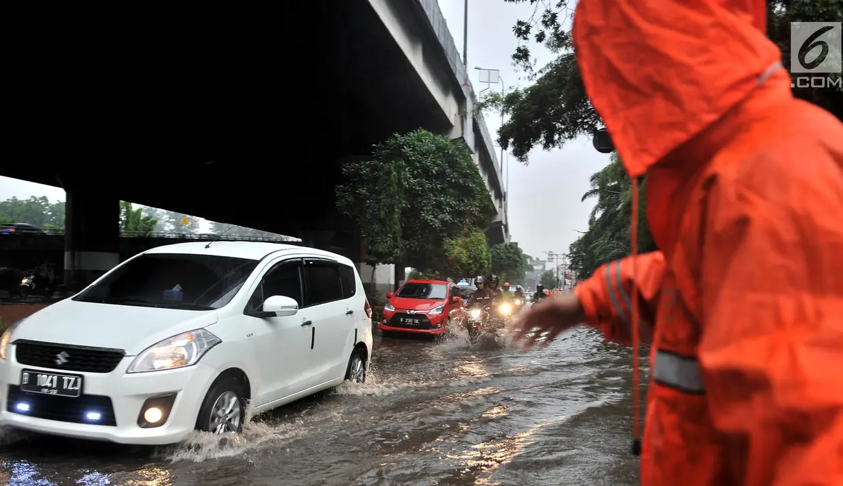 Petugas PPSU mengatur lajur kendaraan saat banjir menggenangi Jalan DI Panjaitan, Jakarta, Senin (3/12). Hujan deras yang mengguyur Jakarta sejak siang tadi menyebabkan banjir menggenangi hingga sebetis orang dewasa. (Merdeka.com/ Iqbal S. Nugroho)