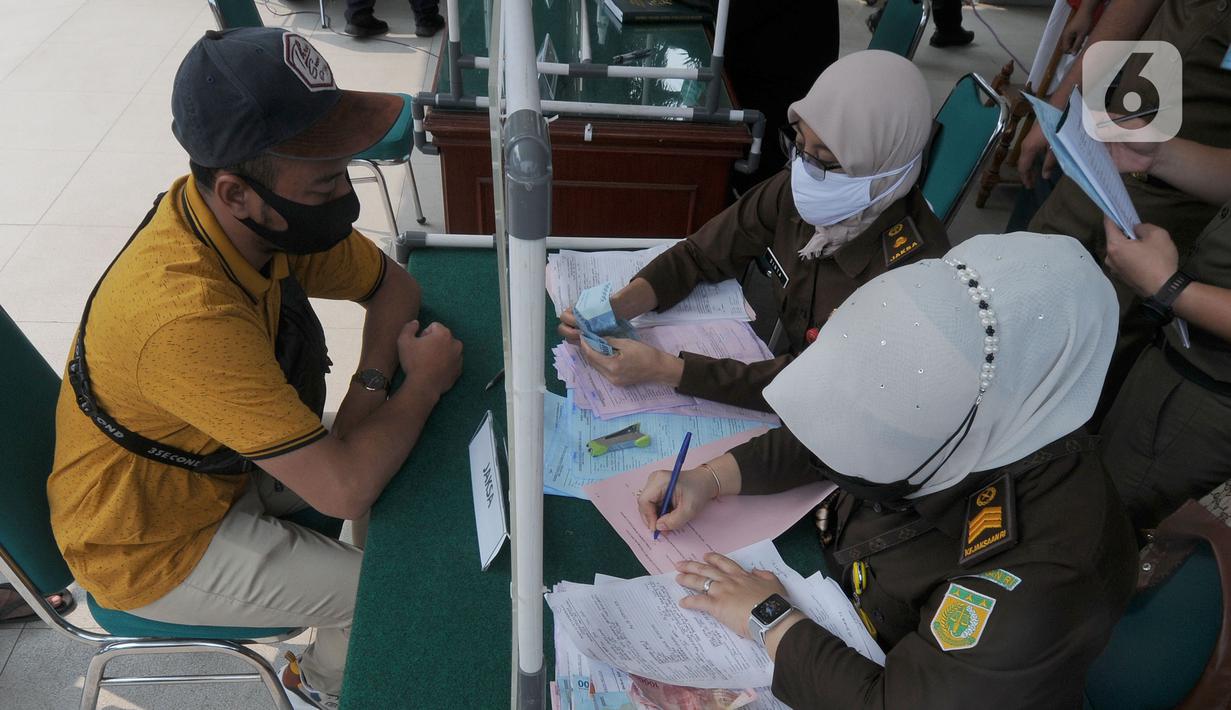 Pelanggar membayar denda saat Sidang Tipiring PPKM Darurat di kantor Kecamatan Pamulang, Tangerang Selatan, Banten, Senin (19/7/2021). Dua puluh empat pelanggar PPKM Darurat diantaranya tidak bermasker dan jam operasional tempat usaha didenda Rp 100 ribu hingga Rp 500 ribu. (merdeka.com/Arie Basuki)