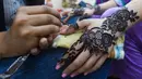 Meski bisa dilakukan setiap hari, tetapi seniman henna akan semakin berjubel di malam perayaan Idul Fitri. (Photo by Asif HASSAN / AFP)