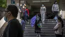 Para komuter yang mengenakan masker berjalan menuruni tangga di stasiun kereta bawah tanah yang baru dibuka kembali di kawasan pusat bisnis di Beijing, China, Selasa (31/5/2022). Otoritas Shanghai mengatakan mereka akan mengambil beberapa langkah besar pada Rabu untuk membuka kembali kota terbesar di China setelah dua bulan penguncian COVID-19. (AP Photo/Mark Schiefelbein)