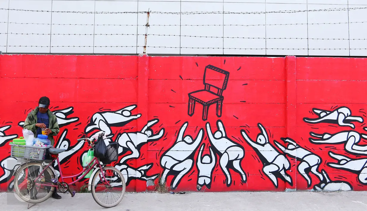 Warga berjualan di depan mural bernuansa politik di Penjaringan, Jakarta, Minggu (7/8). Jelang Pilkada 2017, sejumlah lokasi di Jakarta dihiasi mural politik. (Liputan6.com/Angga Yuniar)