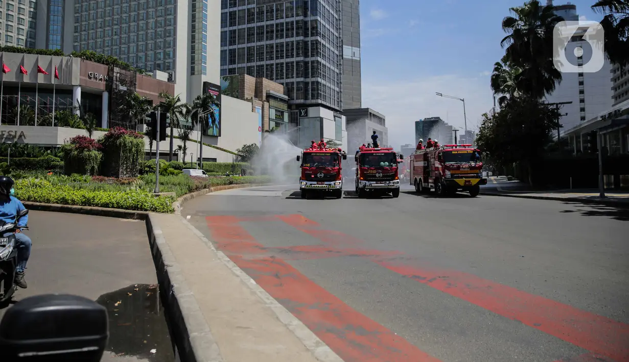 Petugas Dinas Pemadam Kebakaran Pemprov DKI melakukan penyemprotan cairan disinfektan di Jalan Thamrin, Jakarta, Selasa (31/3/2020). Penyemprotan yang dilakukan terus menerus itu untuk meminimalisir penyebaran COVID-19 di ruang udara dan ruas jalan. (Liputan6.com/Faizal Fanani)