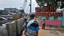 Warga melihat pengerjaan dinding turap di depan RPTRA Krendang yang ditutup sementara, Jakarta, Kamis (25/10). Penutupan RPTRA Krendang demi alasan keselamatan warga akibat adanya proyek pemasangan dinding turap Kali Duri. (Merdeka.com/Iqbal Nugroho)