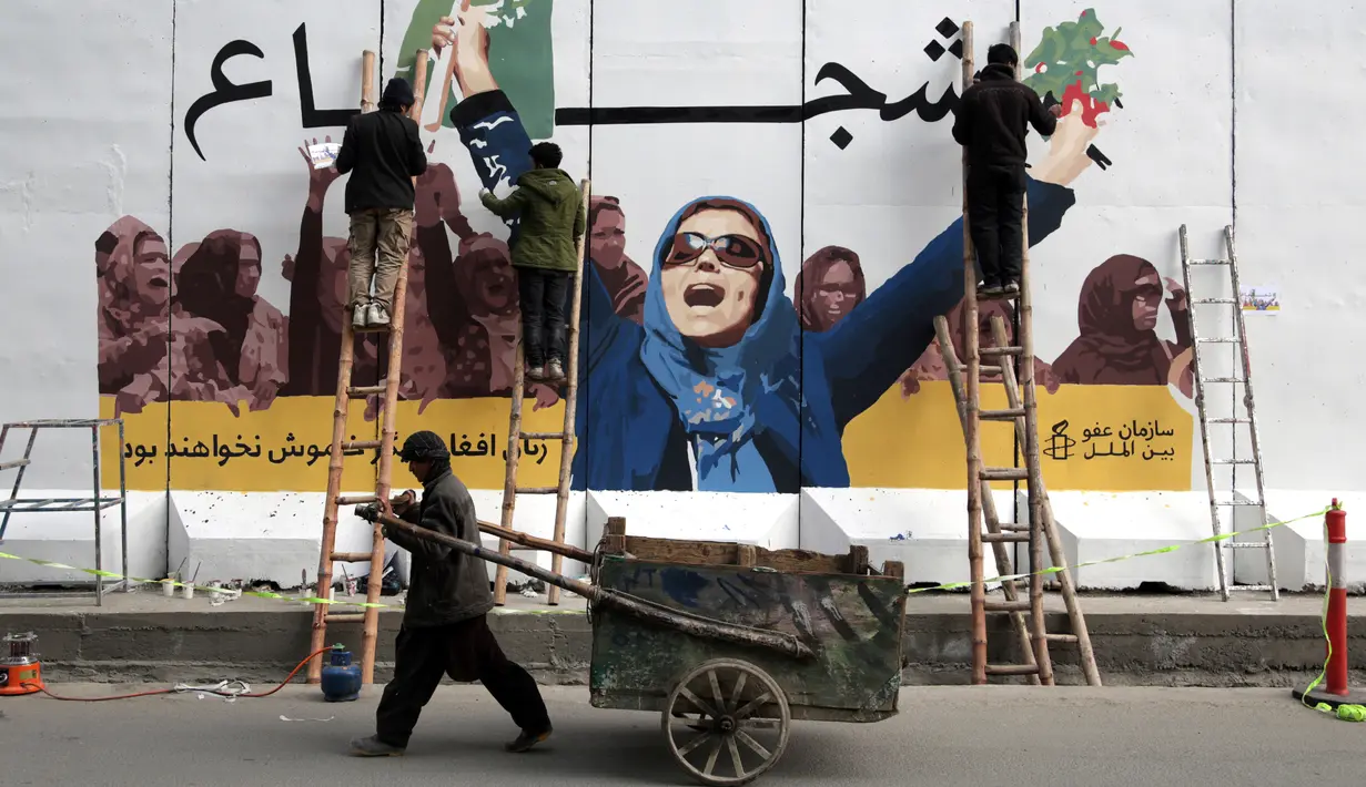 Seniman Afghanistan menggambar mural pada pagar Kementerian Urusan Perempuan saat memperingati Hari Perempuan Internasional di Kabul, Jumat (8/3). (AP Photo/Rahmat Gul)