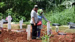 Peziarah berdiri di sisi makam korban yang diduga terinfeksi virus COVID-19 di TPU Pondok Ranggon, Jakarta, Minggu (24/5/2020). Berdasar data yang diumumkan pemerintah per 24 Mei 2020, 22.271 orang positif Corona, 1.372 meninggal dunia dan 5.402 dinyatakan sembuh. (Liputan6.com/Helmi Fithriansyah)