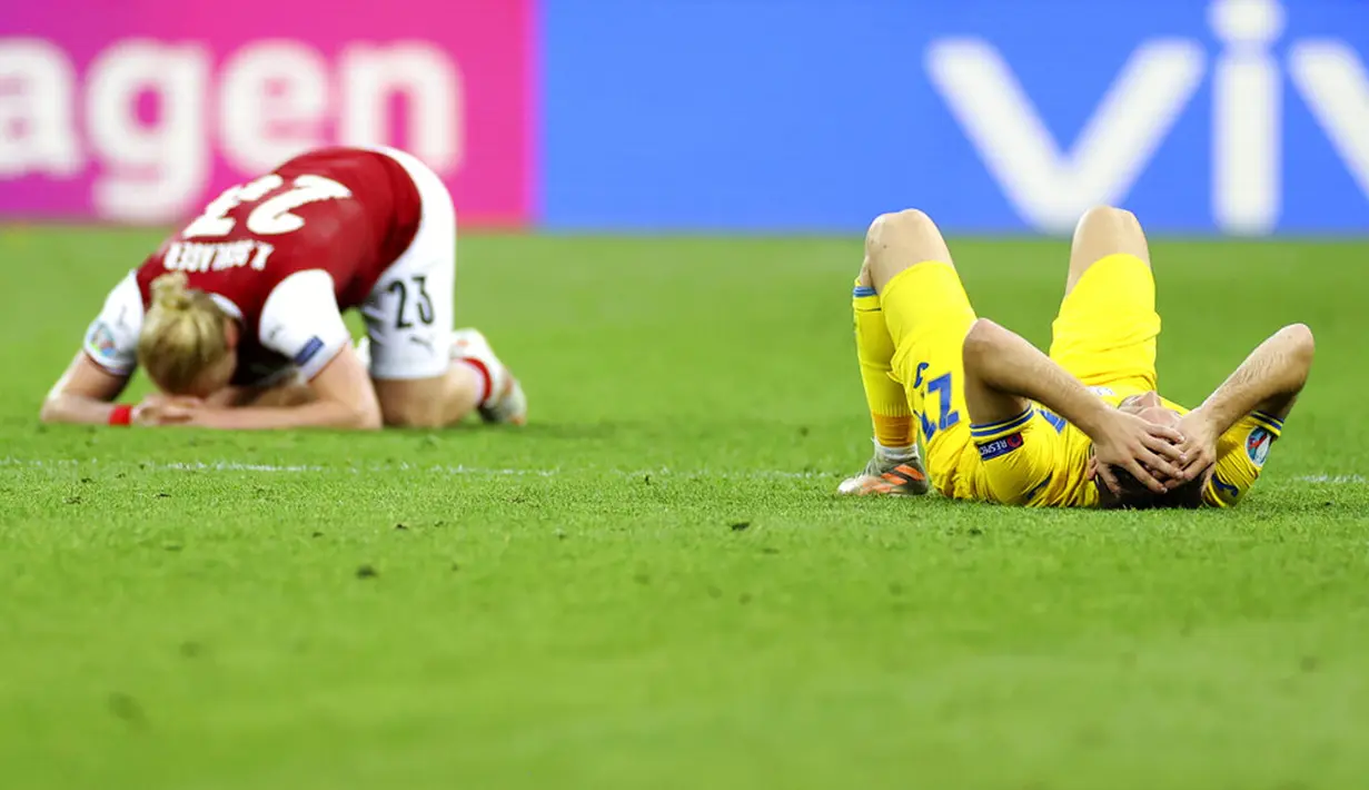 Pemain Ukraina Oleksandr Karavayev (kanan) dan pemain Austria Xaver Schlager terbaring di lapangan usai pertandingan Grup C Euro 2020 di Stadion National Arena, Bucharest, Rumania, Senin (21/6/2021). Ukraina kalah 0-1. (Marko Djurica/Pool via AP)