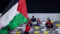 Seorang suporter Indonesia mengibarkan bendera Palestina saat laga kedua Grup A Piala Dunia U-17 2023 antara Timnas Indonesia U-17 menghadapi Timnas Panama U-17 di Stadion Gelora Bung Tomo (GBT), Surabaya, Senin (13/11/2023). (Bola.com/Bagaskara Lazuardi)