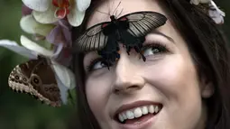 Jessie May Smart tersenyum saat berpose dengan yang menghinggapi wajahnya, sebelum pembukaan, "Butterflies in the Glasshouse", di RHS Wisley di Wisley, Inggris, (13/1). Ditempat ini sedikitnya terdapat 6.000 kupu-kupu yang hidup bebas. (AFP/Adrian Dennis)