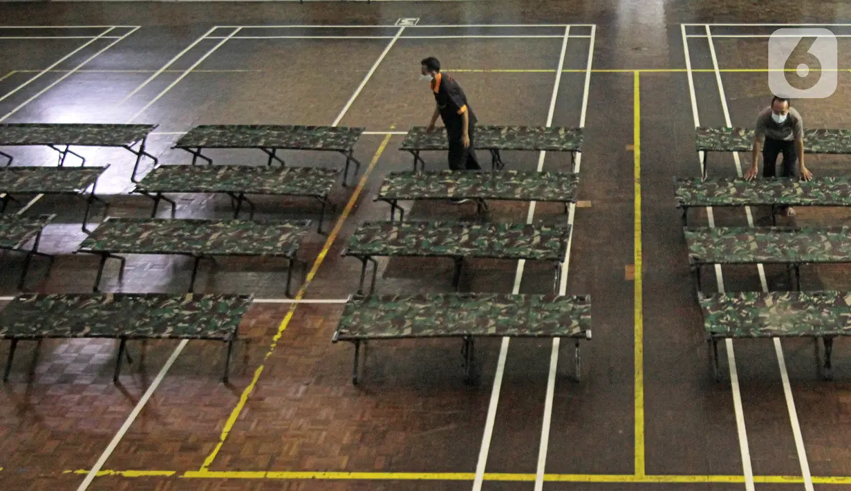 Petugas menyiapkan tempat singgah sementara bagi warga yang baru kembali ke Jakarta di GOR Cipayung, Jakarta, Selasa (18/5/2021). GOR ini jadi tempat singgah bagi mereka yang tidak memiliki tempat layak untuk isolasi mandiri sambil menunggu hasil tes swab antigen/PCR. (Liputan6.com/Herman Zakharia)