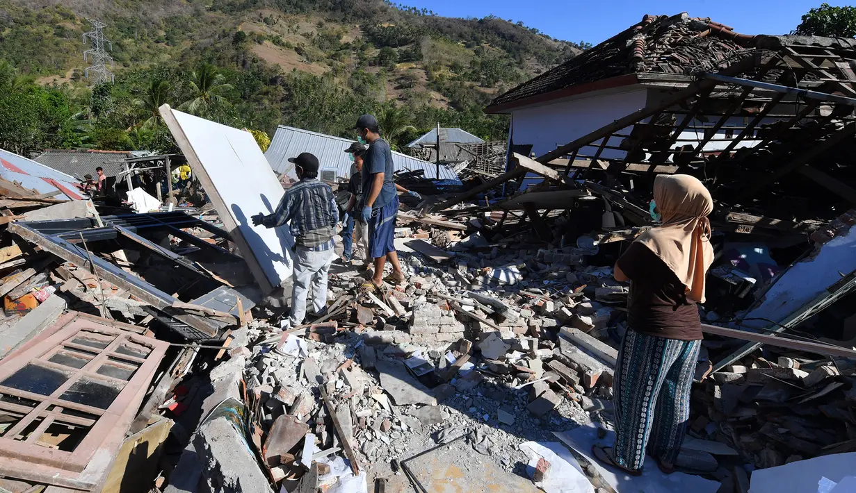 Orang-orang membersihkan puing-puing dari bangunan rumah yang rusak di Menggala, Lombok Utara, Rabu (8/8). Laporan terakhir mengatakan, gempa Lombok telah memakan 105 korban jiwa, dan lebih 70.000 orang kehilangan tempat tinggal. (AFP/ADEK BERRY)