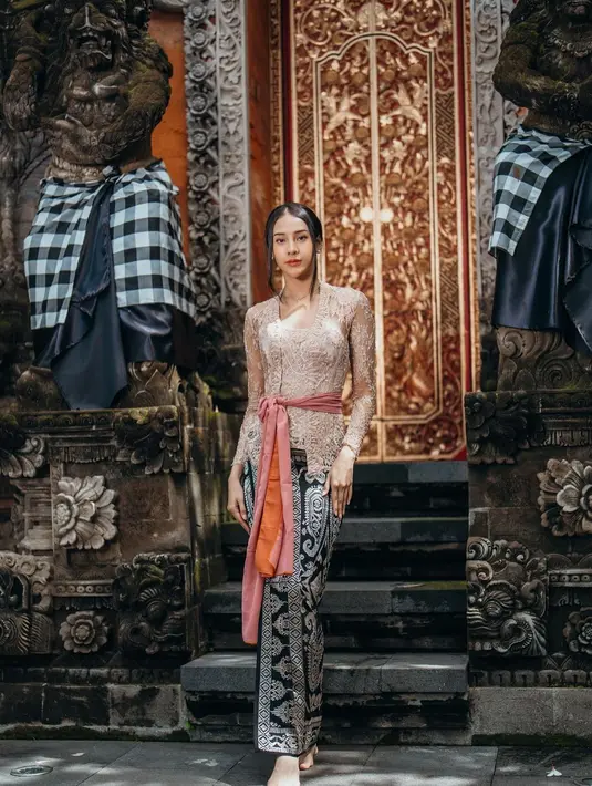 Anya terlihat anggun dalam balutan kebaya Bali berwarna cream. Kebaya tersebut ia padukan bersama obi berwarna pink salmon. Sementara untuk bawahan, Anya memilih kain songket berwarna hitam-emas. [@anyageraldine]