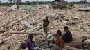 Dalam catatan Badan Nasional Penanggulangan Bencana (BNPB), bencana banjir dan longsor di Aceh Tamiang mengakibatkan kerusakan sebanyak 2.800 unit rumah, 127 fasilitas umum, 62 gedung atau kantor, 54 fasilitas pendidikan, 40 fasilitas kesehatan, 33 rumah ibadah, dan dua jembatan. Tampak dalam foto, warga beristirahat sambil mencari sisa-sisa rumah mereka yang terkubur di bawah tumpukan pohon tumbang yang disapu banjir bandang, di desa Lintang Baru di Aceh Tamiang, Sumatera Utara, pada Kamis 11 Desember 2025. (Aditya Aji/AFP)