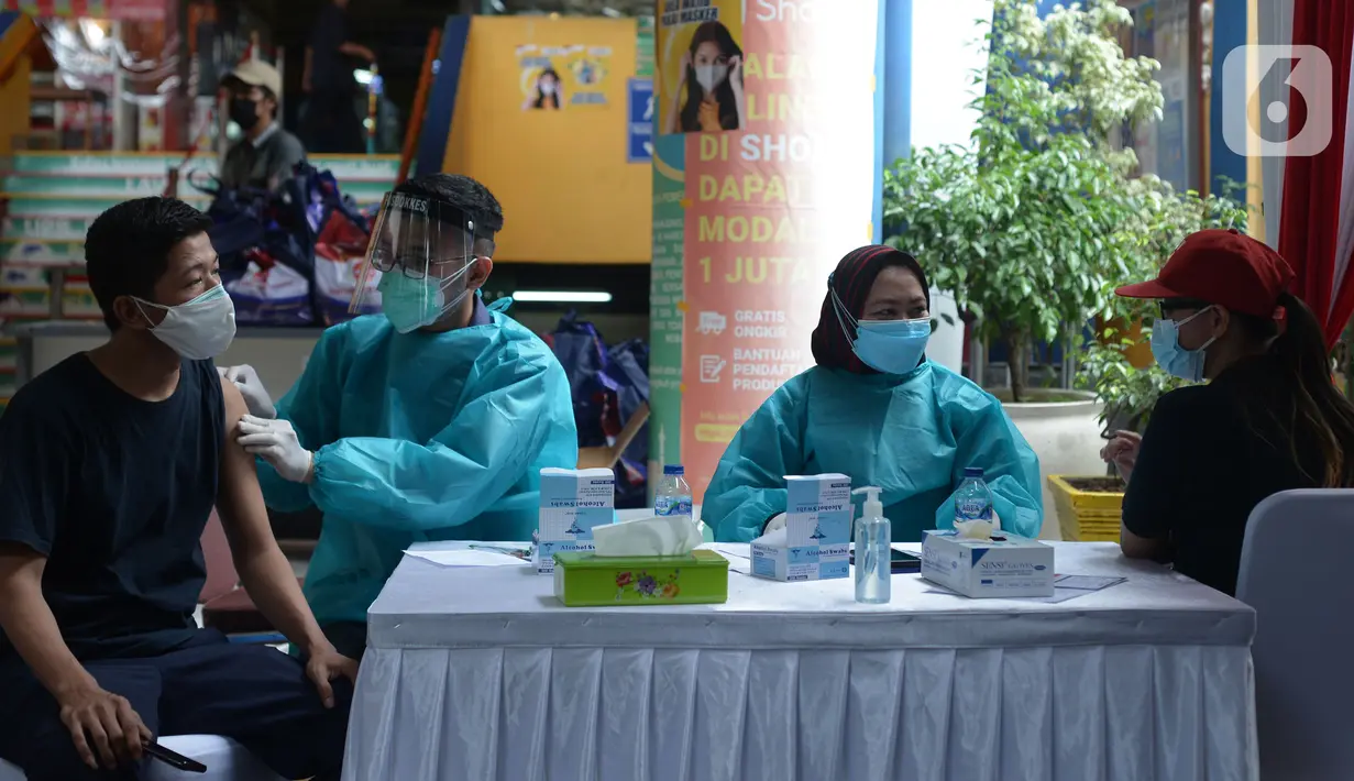 Polisi menyuntikkan vaksin virus corona COVID-19 kepada pedagang Pasar Induk Kramat Jati di Jakarta Timur, Kamis (22/7/2021). Sebanyak 250 pedagang Pasar Induk Kramat Jati menjalani vaksinasi guna menekan penyebaran COVID-19. (merdeka.com/Imam Buhori)