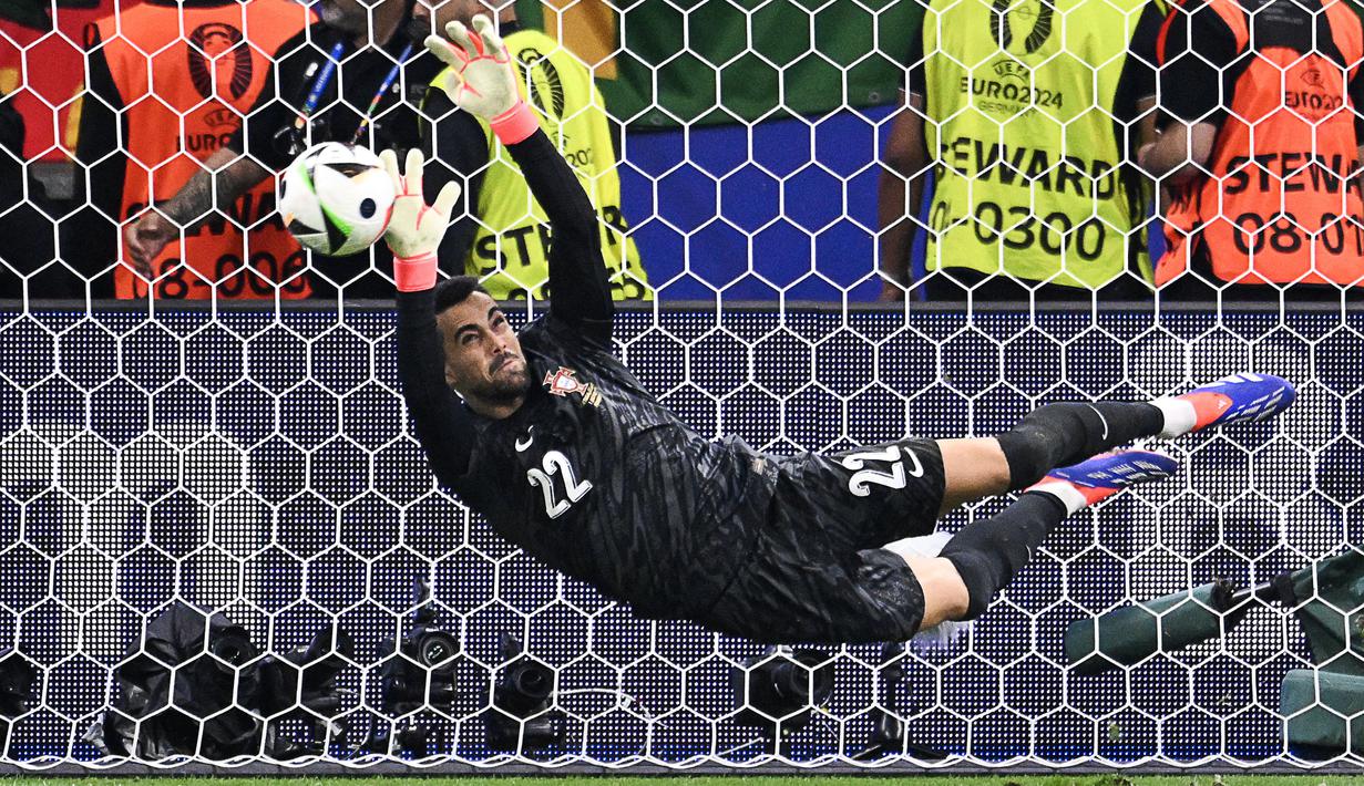 Kiper Portugal, Diogo Costa menggagalkan tendangan pemain Slovenia, Jure Balkovec pada babak adu penalti saat babak 16 besar Euro 2024 di Frankfurt Arena, Frankfurt, Jerman, Senin (02/07/2024) WIB. (AFP/Kirill Kudryavtsev)