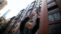 Seorang wanita memukul panci  mengungkapkan rasa terima kasih dan hormat kepada para petugas kesehatan di New York, AS (16/4/2020). Setiap malam pukul 19.00 waktu setempat, warga bertepuk tangan menyemangati pekerja esensial mendukung dan mengapresiasi selama pandemi COVID-19. (Xinhua/Michael Nagle)