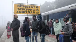 Penumpang menunggu kereta api di tengah kabut tebal selama hari yang dingin di stasiun kereta api di Amritsar, India (30/12/2019). (AFP/Narinder Nanu)