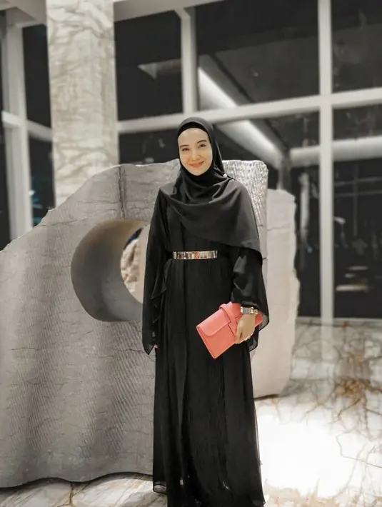 Perpaduan gamis hitam dengan hijab senada serta belt berwarna emas membuat penampilan Zaskia makin elegan. Tas tangan dan sepatu dengan aksen senada juga makin mempermanis penampilannya. (Liputan6.com/IG/@zaskiasungkar15)