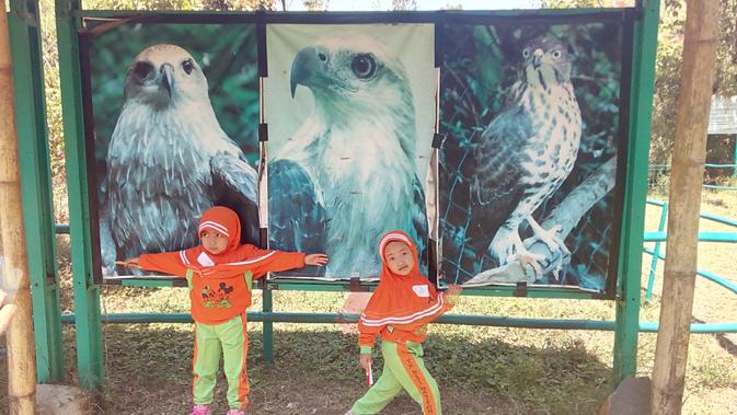 Dua siswa peserta lomba menggambar Garuda, tengah berfose di depan gambar Garuda di kawasan Konservasi Elang Kamojang, Garut (Liputan6.com/Jayadi Supriadin)