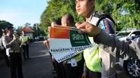 Petugas polisi menunjukkan stiker bergambar bendera Indonesia dan Arab Saudi selama persiapan menyambut kedatangan Raja Salman bin Abdulaziz di Nusa Dua, Bali (2/3). (AFP Photo / Sonny Tumbelaka)