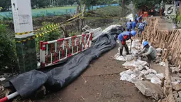 Petugas Sudin Sumber Daya Air Jakarta Timur melakukan perbaikan jalan ambles di Jalan Al-Mujahidin, Cipinang, Pulogadung, Jakarta Timur, Rabu (21/2). Jalan tersebut ambles sepanjang 30 meter dan kedalaman 1,5 meter. (Liputan6.com/Arya Manggala)