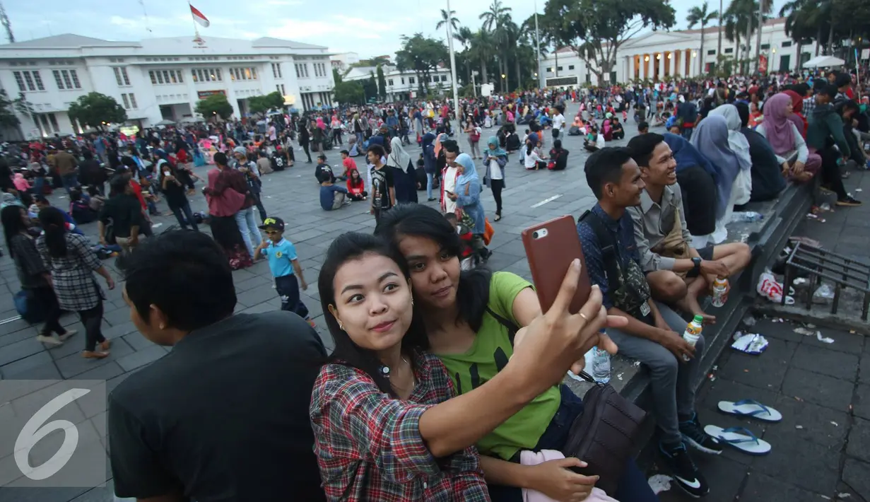Sejumlah pengunjung berselfie di kawasan wisata Kota Tua, Jakarta, Senin (12/12). Kota Tua masih menjadi salah satu destinasi wisata bagi warga Jakarta dan sekitarnya untuk menghabiskan waktu liburan. (Liputan6.com/Immanuel Antonius)