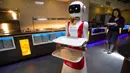 Leah Hu menunjukkan penggunaan robot pengganti pelayan sebagai bagian dari uji coba langkah-langkah aturan jaga jarak di restoran keluarga Royal Palace, Belanda, 27 Mei 2020. Robot ini bertugas menyapa pelanggan, menyajikan makanan dan minuman dan mengembalikan alat makan. (AP/Peter Dejong)