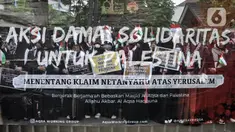 Refleksi pada kaca memperlihatkan massa yang tergabung dalam Aqsa Working Group (AWG) membentangkan poster dan bendera Palestina serta Indonesia saat menggelar Aksi Damai Solidaritas untuk Palestina di Kantor Kedutaan Besar Palestina untuk Indonesia, Menteng Jakarta Pusat, Senin (29/5/2023). (merdeka.com/Iqbal S. Nugroho)