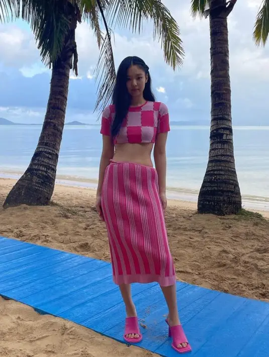 Jennie Blackpink tampil serba pink saat berada di pantai. Mengenakan atasan crop dipadukan midi skirtnya. [@jennierubyjane]